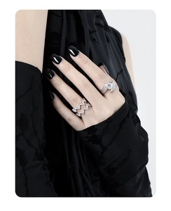 Macro shot of silver feather ring and zigzag crystal band on model hand with black nails