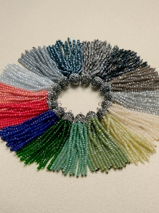 Macro view of colorful 2mm crystal bead tassels with rhinestone caps arranged in a circle