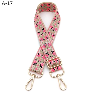 Close-up of pink morning glory embroidery and golden metal hooks on adjustable bag strap