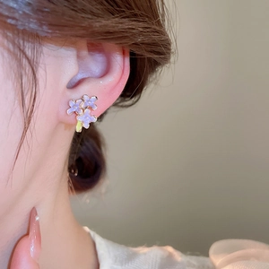 Primo piano di una modella con orecchini a lobo a fiori in smalto viola e oro