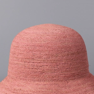 Macro detail of high-quality coral pink hand-woven raffia texture on a wide-brim sun hat