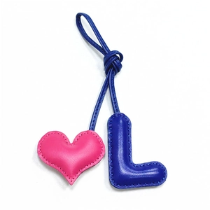 Detail of pink heart and blue leather letter L charm with handmade stitching