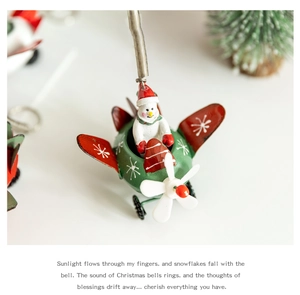 Macro shot of metal Christmas plane ornament with snowman pilot and green snowflake body