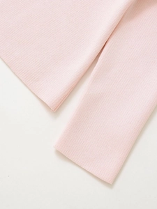 Gros plan sur un tricot rose clair doux avec coutures fines et texture côtelée