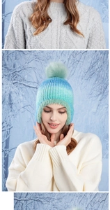 Detailed close-up of gradient knit hat with plush earflaps and a large faux fur pom-pom