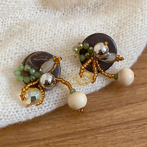 Détail de boucles d'oreilles rondes faites main avec perles en bois et touches vertes