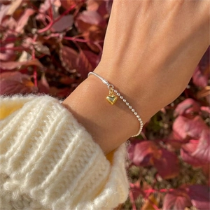 Detail view of S925 silver double chain bracelet with a gold 3D heart-shaped pendant