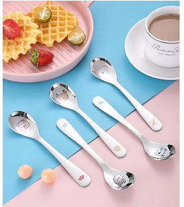 Detailed view of five stainless steel children's spoons with cute cartoon animal engravings
