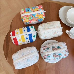 Five assorted quilted cotton cosmetic bags with floral and bear patterns on a wooden table