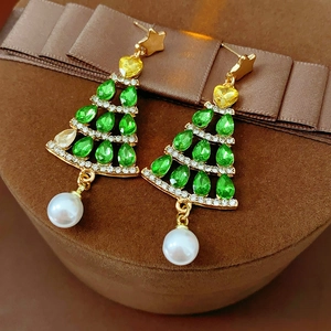 Detailed view of Christmas tree earrings with green crystals and pearls on a brown box