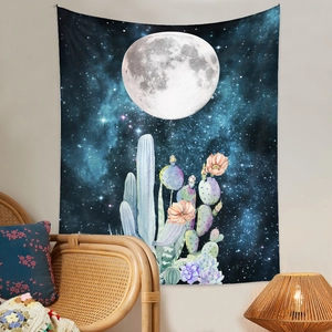 Détail d'une tapisserie lune et cactus suspendue au-dessus d'une chaise en osier