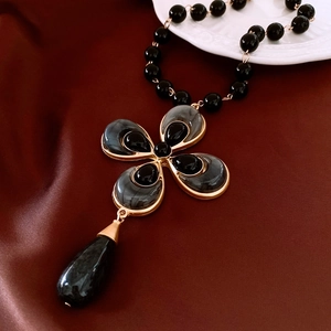 Detail of vintage flower necklace with golden petals, black beads, and large teardrop pendant