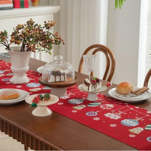 Festive red Christmas table runner with candy jacquard motifs on a wooden dining table