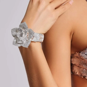Dettaglio dell'ampio bracciale argentato con grande rosa di cristallo indossato sul polso