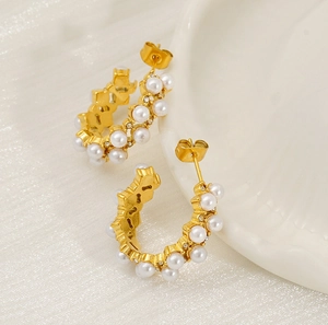 Macro detail of golden C-shaped earrings with double-row pearls and sparkling crystals