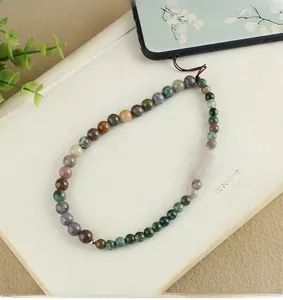 Detail of beaded phone wrist strap with natural agate and turquoise on a book