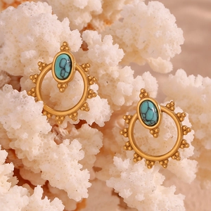 Macro detail of Bohemian gold hoop earrings with oval turquoise and beaded textures