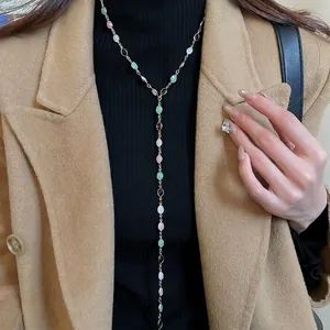 Elegant gold-tone Y-necklace featuring pastel resin stones on a model in knitwear