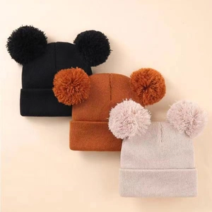 Detailed knit texture and soft double pompoms on black, caramel, and beige beanies