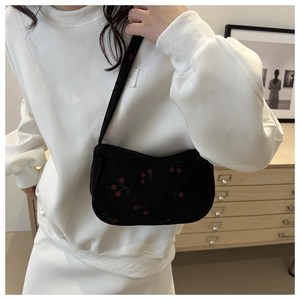 Dettaglio della borsa a spalla in velluto nero con ricamo di ciliegie rosse per look casual