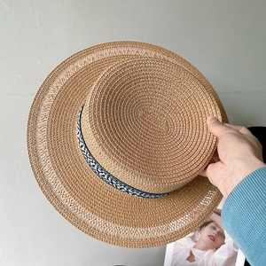 Dettaglio di un cappello di paglia a cima piatta con nastro floreale blu e trama fine