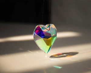 Detail of heart-shaped crystal suncatcher prism reflecting vibrant rainbow light patterns