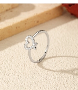 Close-up of heart-shaped silver ring with small diamonds on a stone and flower background