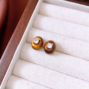 Detailed shot of tiger eye stud earrings with cubic zirconia in a jewelry box