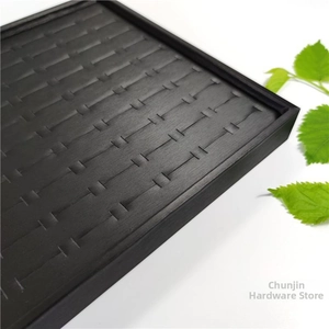 Detailed view of black jewelry display tray with wood grain texture and multiple ring slots