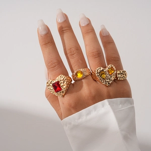 Detail of four vintage gold resin rings with hammered texture and red yellow gemstones