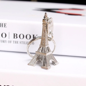 Silver Eiffel Tower keychain with Paris engraving on white vintage book background