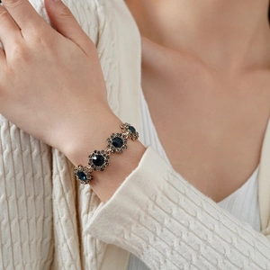 Détail d'un bracelet vintage fleur en or antique orné de pierres précieuses bleu foncé