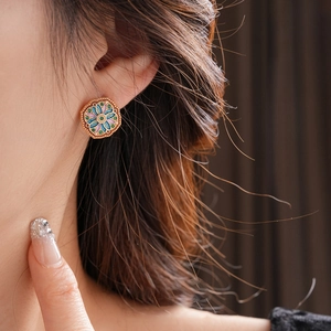 Close-up of a vintage hexagonal enamel floral earring with gold plating on ear