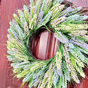 Close-up of colorful lavender wreath hanging on a dark wood door for home wall decor