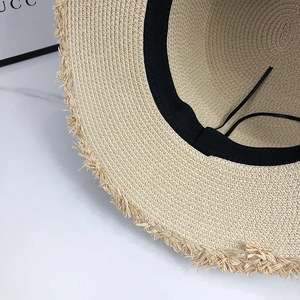 Detail of straw sun hat featuring a frayed edge design and adjustable inner strap