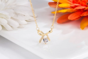 Detail of gold bow necklace with heart crystal pendant and sparkling stones on white
