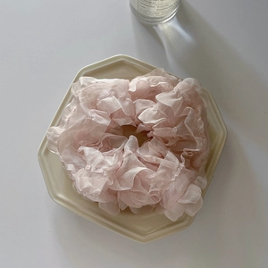 Detail of light pink organza scrunchie with ruffled lace texture on a ceramic tray