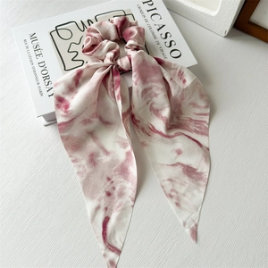 Close-up of red polka dot chiffon ribbon scrunchie placed on artistic books