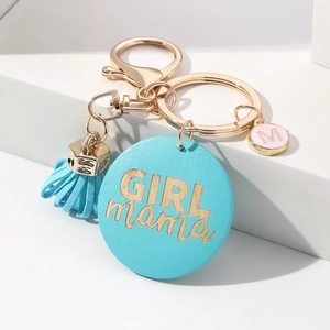 Detail of blue Girl Mama tassel keychain with golden M initial charm on white background