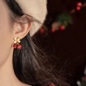 Elegant red cherry bow earrings on model showing a festive winter look and golden bow