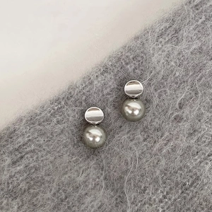 Macro detail of French style grey pearl earrings on a soft grey textured knit background