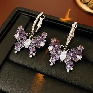 Macro shot of silver zircon butterfly earrings with purple gradient gemstones in box