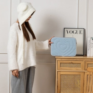 Light blue quilted heart pattern 13-inch laptop sleeve with zipper closure on wood shelf