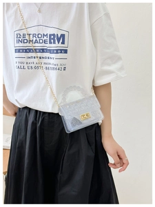 Detail of transparent PVC jelly bag featuring beaded handle and gold chain strap