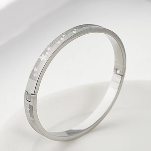 Dettaglio dei motivi a stella incisi e della trama a griglia sul bracciale in acciaio titanio