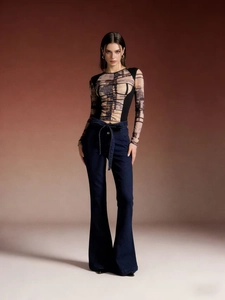 Full body view of high waist flared jeans paired with a geometric print patchwork long sleeve top