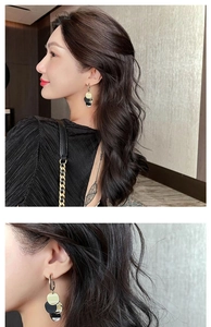 Detail of vintage geometric earrings with gold, black, and white circular tassel drops