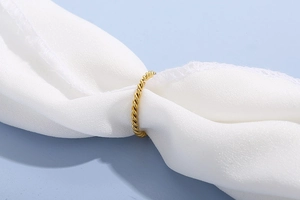 Macro shot of gold twisted rope ring texture on white fabric over a blue background