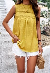 Detail of yellow sleeveless blouse featuring lace trim and textured polka dot fabric design