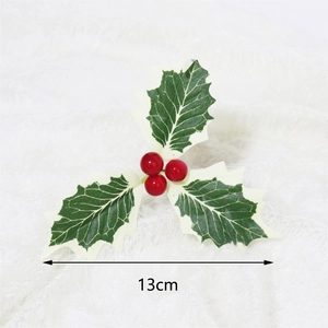 Close-up of artificial Christmas holly leaves with red berries on white plush surface